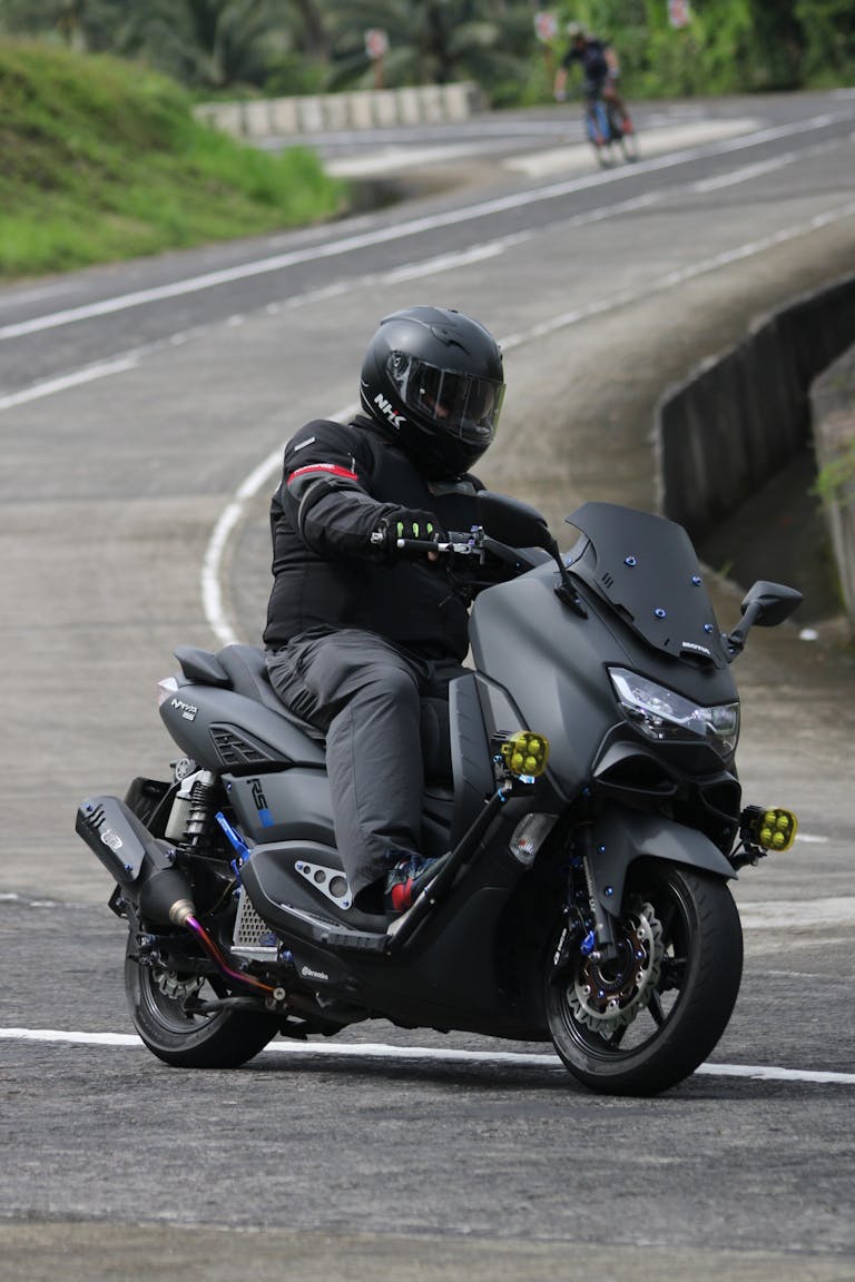 Motorcyclist in protective gear navigating a curvy road on a sports bike.